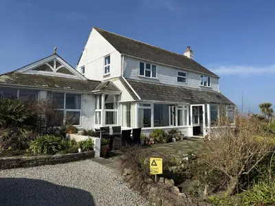 a white house with a sign in front of it at 2 The Links in St Ives