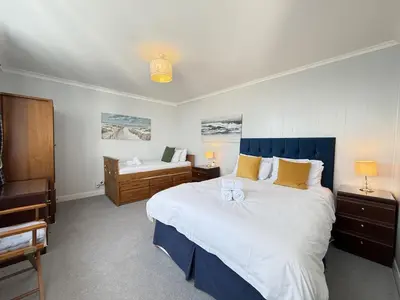 a bedroom with a large bed with a blue headboard at 2 The Links in St Ives