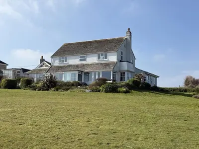 a large white house with a large grass field at 1 The Links in St Ives