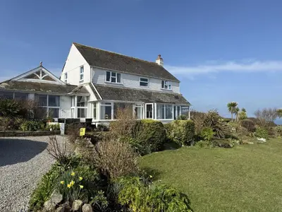 a large white house with a yard with flowers at 1 The Links in St Ives