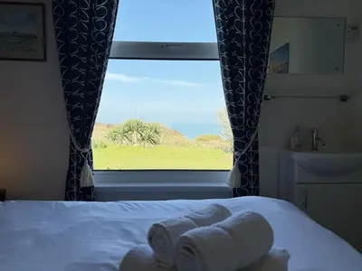 a bedroom with a bed and a window with towels at 1 The Links in St Ives