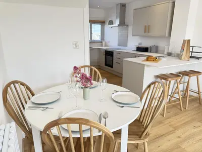 a white kitchen with a white table and chairs at 5 Ayr Court in St Ives