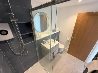 a bathroom with a shower with a sink and a mirror at 5 Ayr Court in St Ives