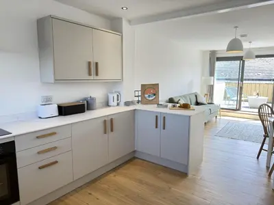 a kitchen with white cabinets and a living room at 5 Ayr Court in St Ives