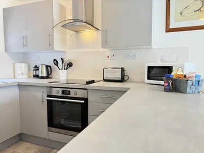 a white kitchen with a stove and a microwave at Gwel an Mor in St Ives