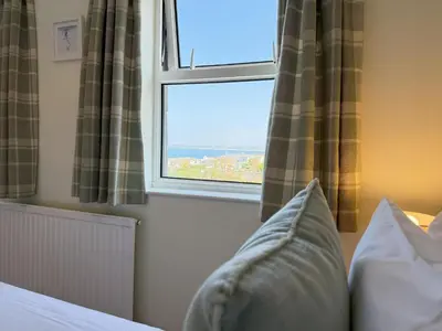 a bedroom with a window with a view of the ocean at Gwel an Mor in St Ives