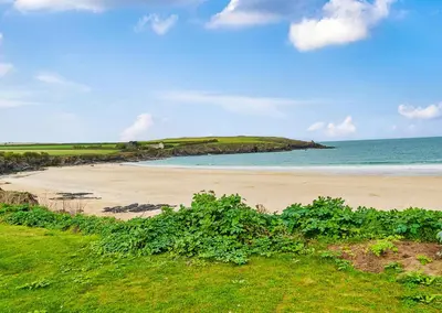 a sandy beach with the ocean in the background at Headlands- Stylish Oceanfront Property on Harlyn Bay in Padstow