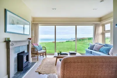 a living room with a couch and a fireplace at Headlands- Stylish Oceanfront Property on Harlyn Bay in Padstow