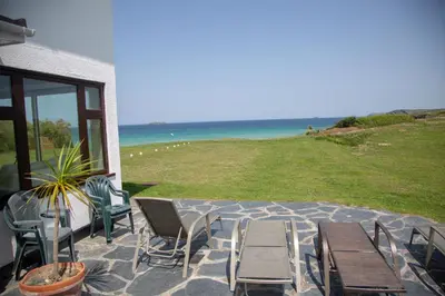 a patio with chairs and tables and the ocean at Headlands- Stylish Oceanfront Property on Harlyn Bay in Padstow