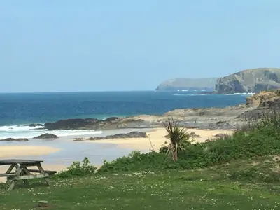 a picnic table sitting on top of a beach at Headlands- Stylish Oceanfront Property on Harlyn Bay in Padstow