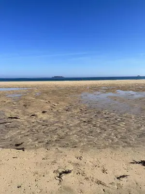 a beach with a lot of sand and water at Headlands- Stylish Oceanfront Property on Harlyn Bay in Padstow