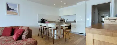 a living room with a couch and a kitchen at 4 Fistral Beach Apartments, Newquay, TR7 1FR in Crantock