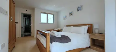 a bedroom with a large bed with white sheets at 4 Fistral Beach Apartments, Newquay, TR7 1FR in Crantock