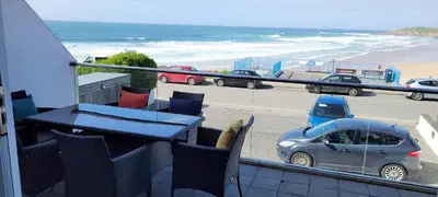 a balcony with a table and chairs and a view of the beach at 4 Fistral Beach Apartments, Newquay, TR7 1FR in Crantock