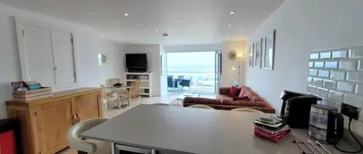 a living room with a table and a couch at 4 Fistral Beach Apartments, Newquay, TR7 1FR in Crantock