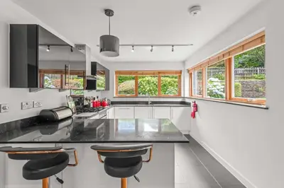 a kitchen with a black counter and some windows at House 19 in Looe