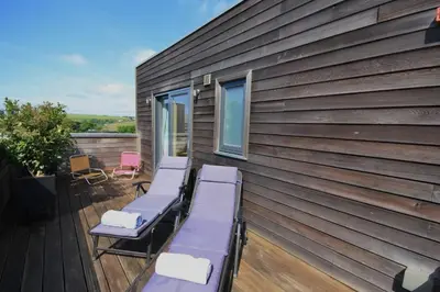 a deck with loungers and chairs on a house at House 19 in Looe