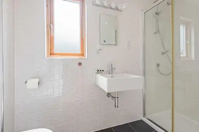 a white bathroom with a sink and a shower at House 19 in Looe
