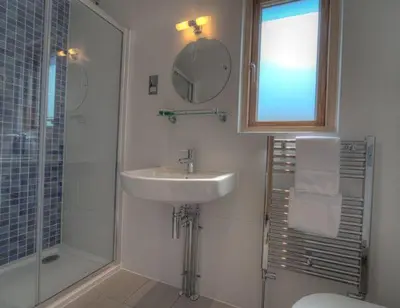 a white bathroom with a sink and a shower at House 21 in Looe