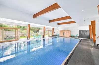 an indoor swimming pool with blue tiles in a house at House 21 in Looe