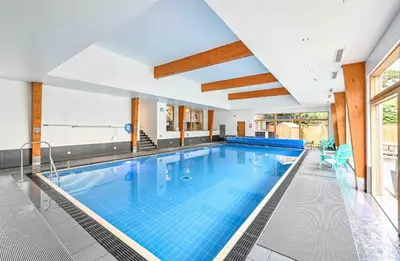 a large swimming pool with blue tiles in a building at House 2 in Looe