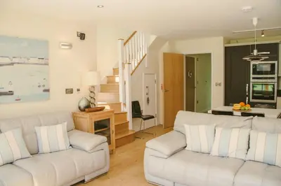 a living room with two white couches and a staircase at House 2 in Looe
