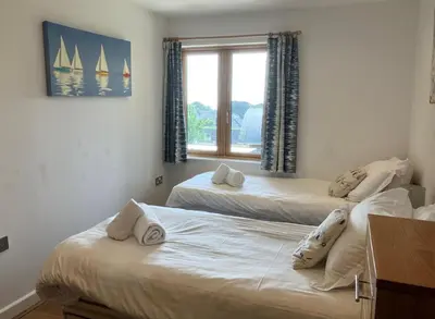 a bedroom with two beds and a window with sailboats on it at House 26 in Looe