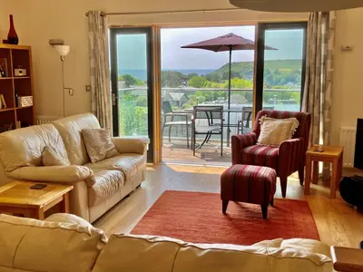 a living room with a couch and a table with an umbrella at House 26 in Looe
