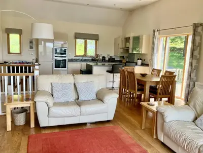 a living room with white couches and a kitchen at House 26 in Looe