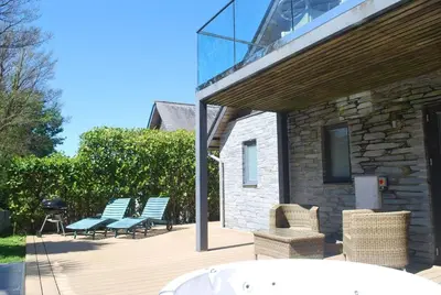 a patio with benches and a grill and a building at House 28 in Looe