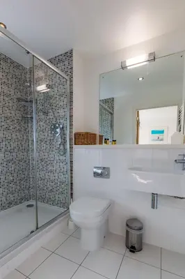 a bathroom with a toilet and a glass shower at House 28 in Looe