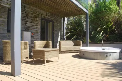 a deck with wicker chairs and a tub on a patio at House 28 in Looe