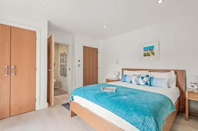a bedroom with a large bed with a blue blanket at House 27 in Looe