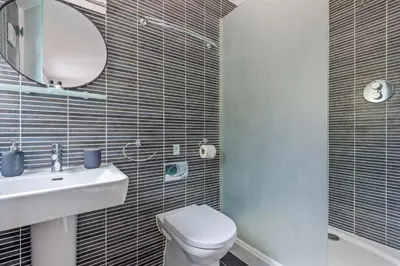a bathroom with a toilet and a sink and a mirror at House 25 in Looe