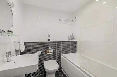 a white bathroom with a tub and a toilet and a sink at House 25 in Looe