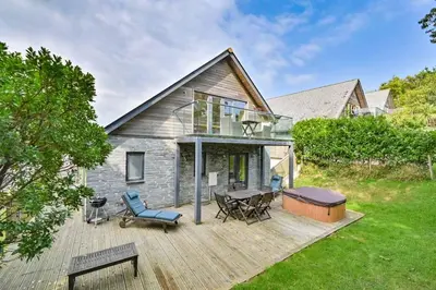 a house with a deck with a table and chairs at House 29 in Looe