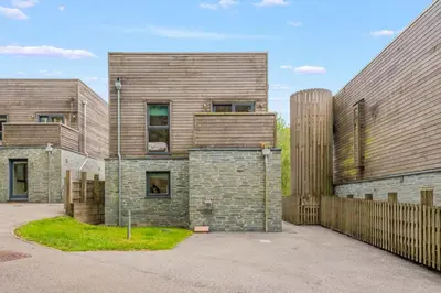 a large house with a wooden fence next to it at House 3 in Looe
