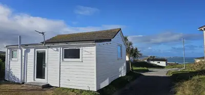 a small white building with a window on a road at D21 Treville, Riviere Towans in Hayle