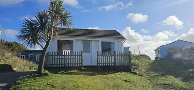 a small house with a fence and a palm tree at D21 Treville, Riviere Towans in Hayle
