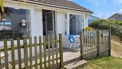 a small white house with a wooden fence at D21 Treville, Riviere Towans in Hayle