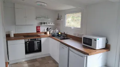 a kitchen with white cabinets and a microwave on a counter at D21 Treville, Riviere Towans in Hayle