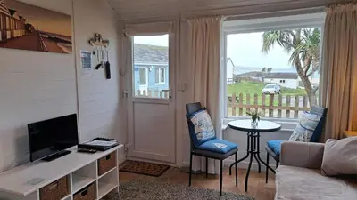 a living room with a couch and a tv and a window at D21 Treville, Riviere Towans in Hayle