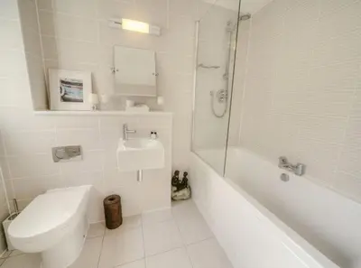 a bathroom with a toilet and a tub and a sink at House 23 in Looe