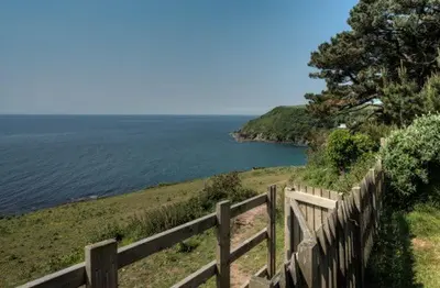a wooden fence next to a body of water at House 23 in Looe