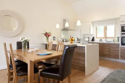 a kitchen and dining room with a wooden table and chairs at House 23 in Looe