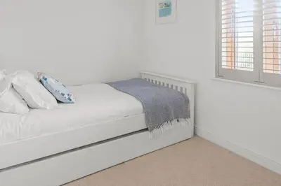 a white bed in a white room with a window at House 24 in Talland
