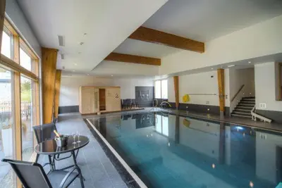 a large swimming pool with a table and chairs at House 24 in Talland