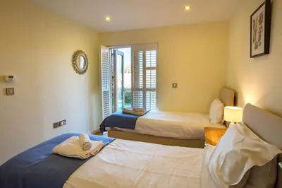 a room with three beds and a window at House 30 in Looe