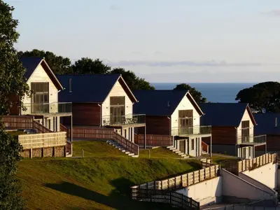a row of houses on a hill with the ocean in the background at House 30 in Looe