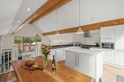 a kitchen with white cabinets and a wooden table at House 31 in Looe